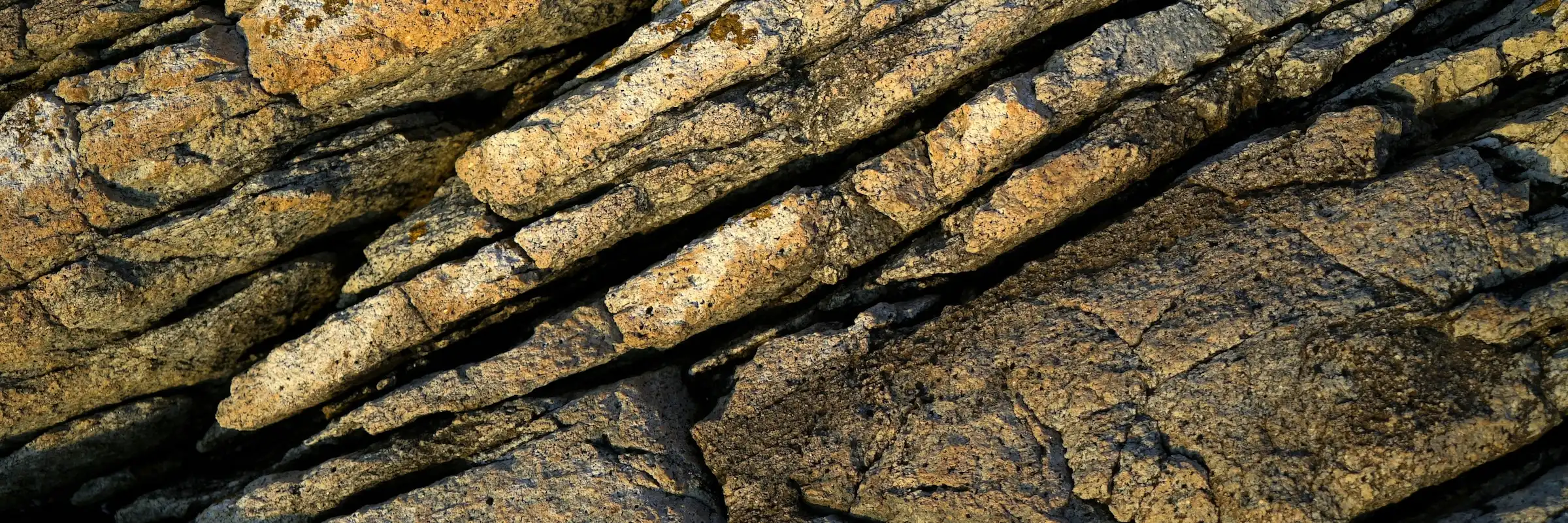 Gesteinsschichten mit eingravierten Linien – Metapher für körperliche Prägungen und Veränderungsprozesse.